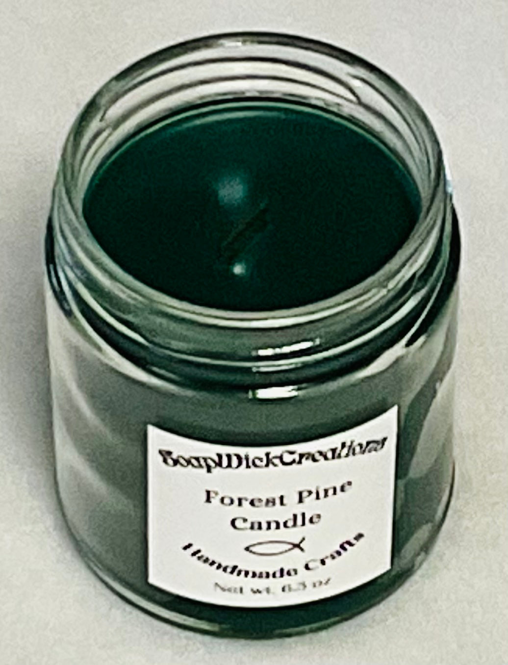 Photograph of a Forest Pine green candle with pine scent with the top remove d.