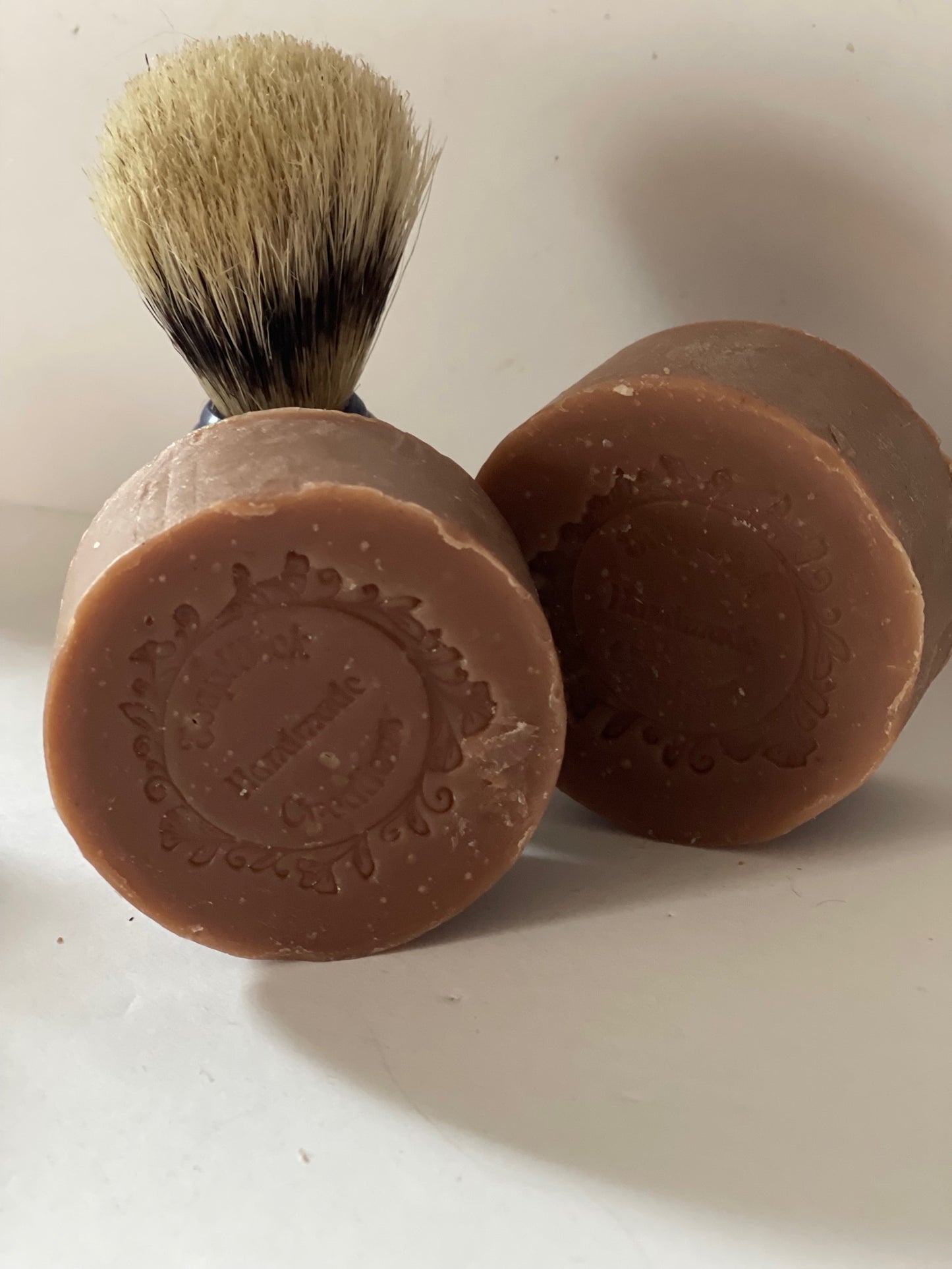 Photo of cherry tobacco men’s soap with a shaving brush in the background
