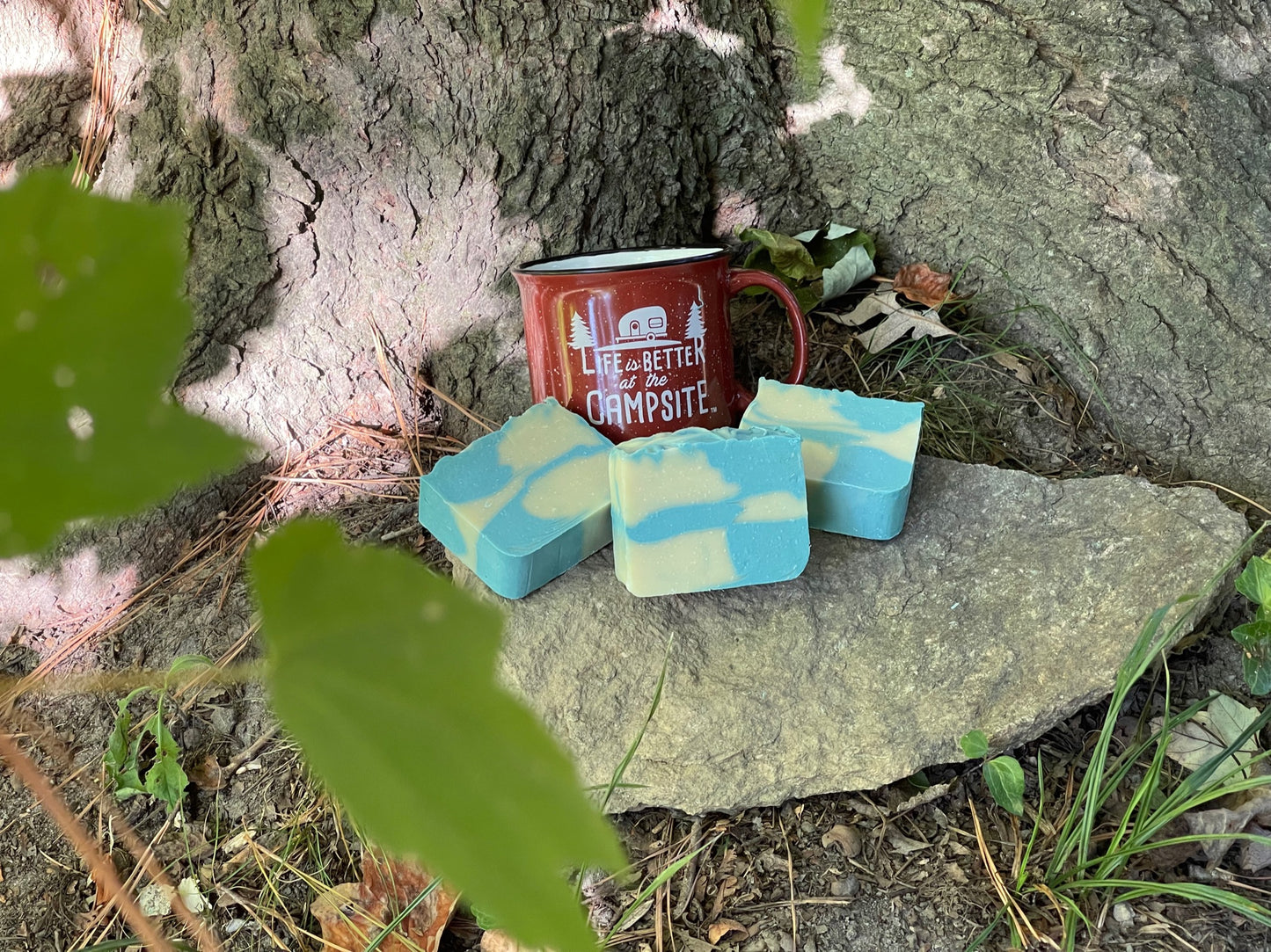 Picture of blue and pale, green citronella soap, sitting on a rock