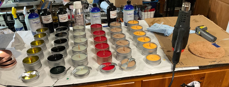 Numerous candles on a countertop in various stages of production.