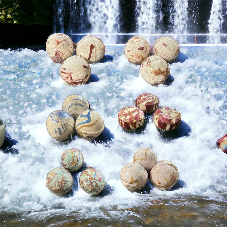 Various scented bath bombs in a stream bed with waterfalls in the background.