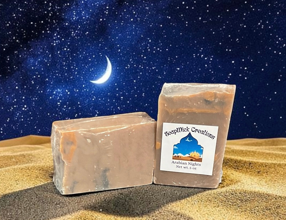 Two bars of Arabian nights bar soap sitting in a bit of sand with an Arabian night sky with a crescent moon behind them.