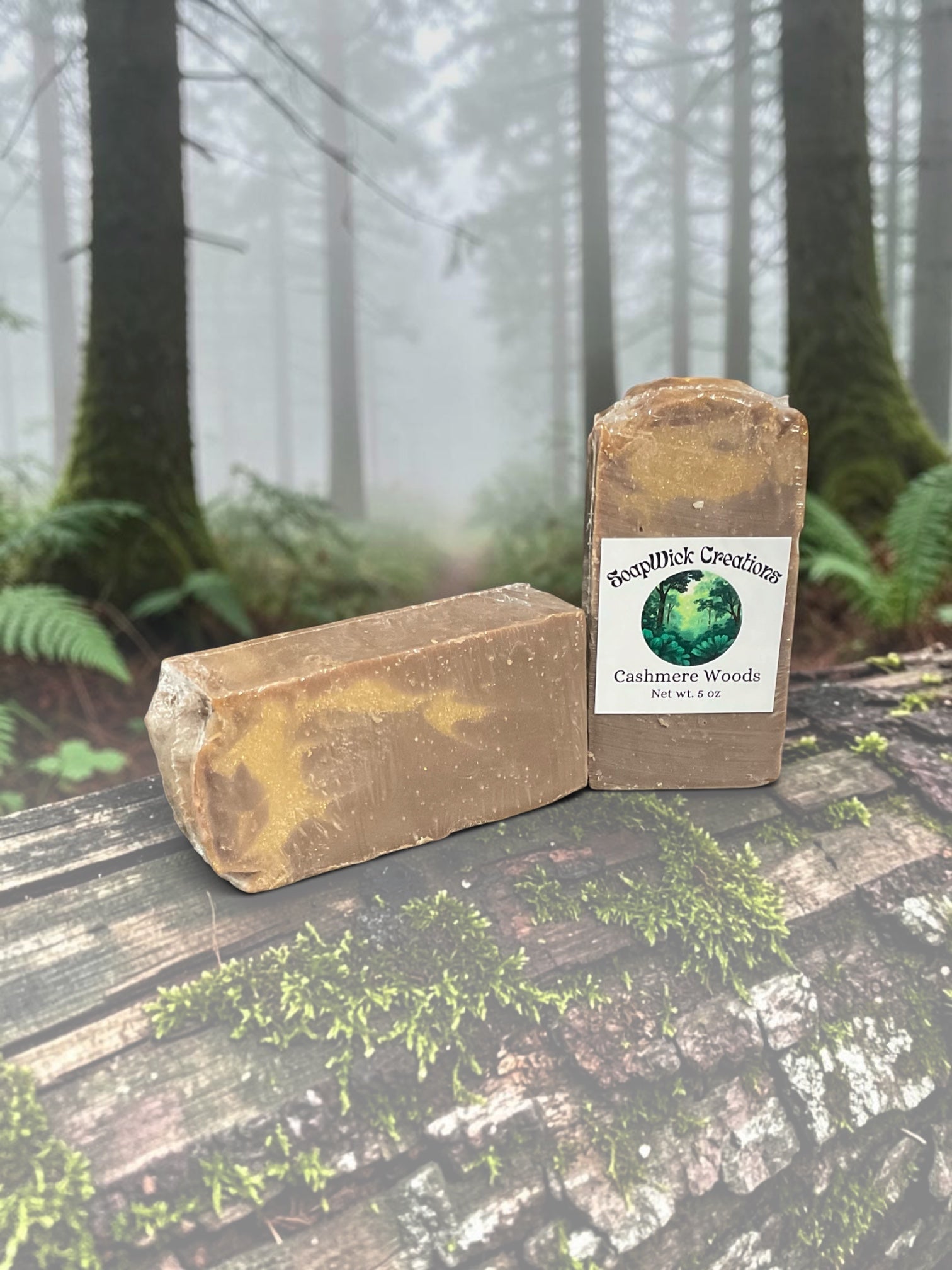 Two brown and cream colored soaps sitting on a fallen log in a misty forest.