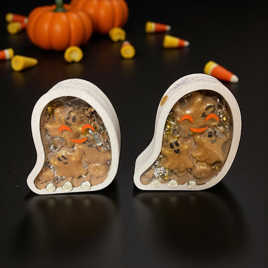 Hand painted and decorated ghost shaped wooden boxes containing glycerin poured soaps with vampire blood scent. In the background is candy corn and pumpkins all sitting on a table top.