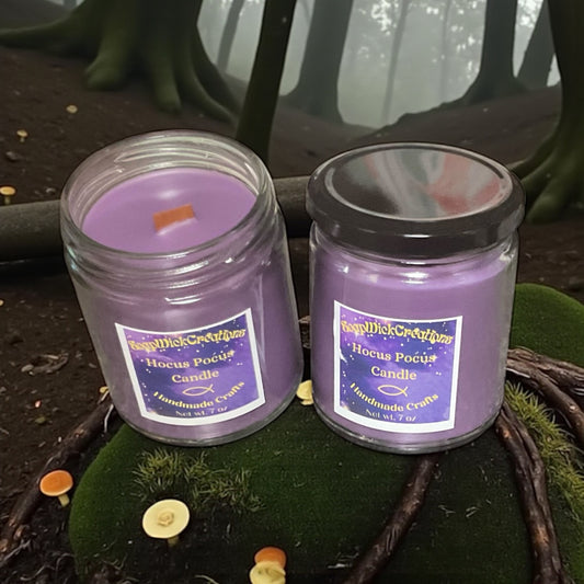 Two purple candles with hocus-pocus scent sitting on a moss covered log with a gloomy forest in the background.