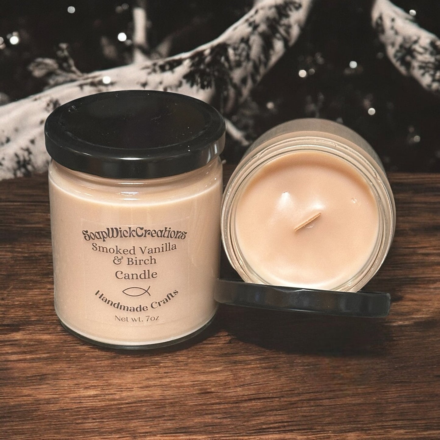 Two Light brown Smoked Vanilla and Birch scented candles in 9oz jars on a wooden table with birch trees in the background.