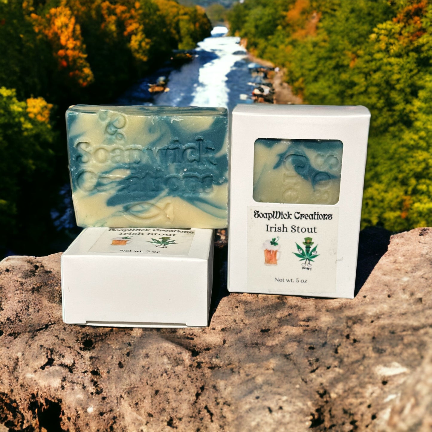 Turquoise and beige colored bar soap, sitting on a rock with a river flowing in the background between rows of forest trees.