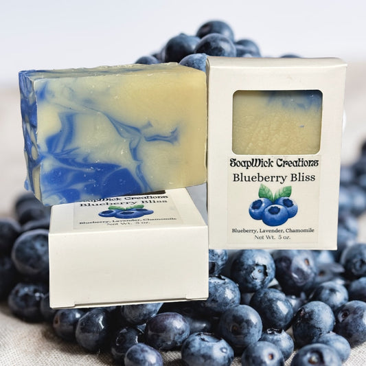 Blue and beige colored, blueberry scented soap bars on a bed of blueberries.