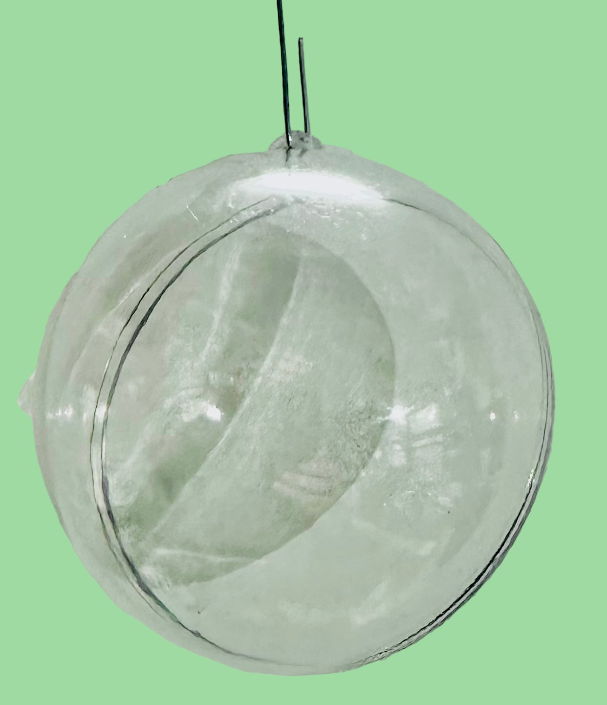 Clear, plastic ornament hanging with a light green background.