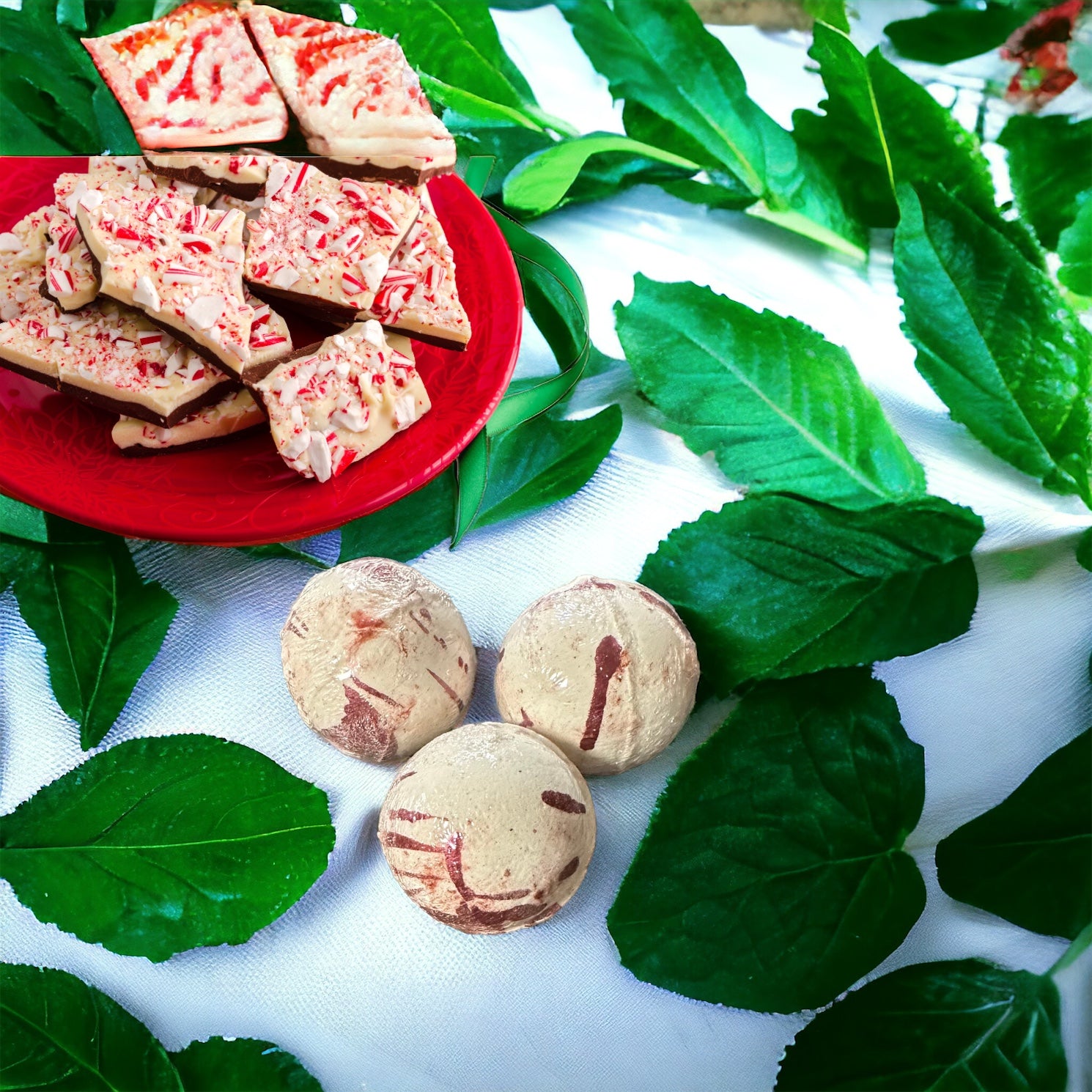 Peppermint scented bath bombs with  peppermint candies on a red plate and peppermint leaves in the background.