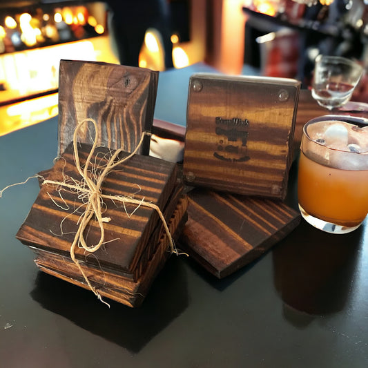 Set a four wooden coasters tied with twine with non-skid rubber feet on the bottom and a drink next to them sitting on a bar top.