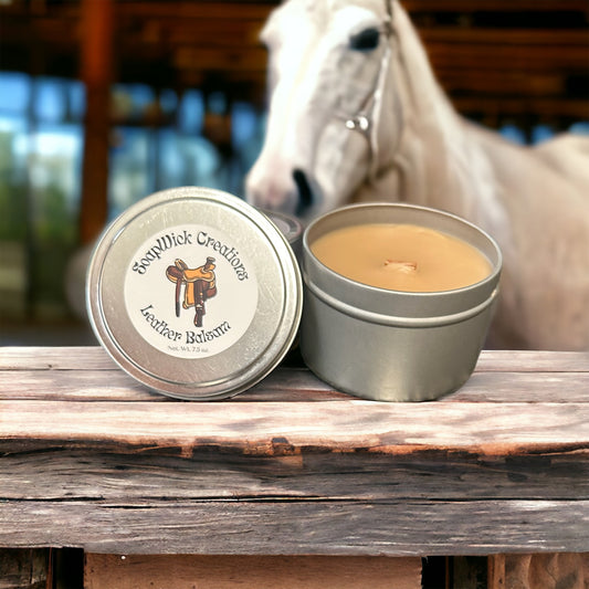 Leather balsam scented candle in a silver metal tin in a stable with a horse in the background.