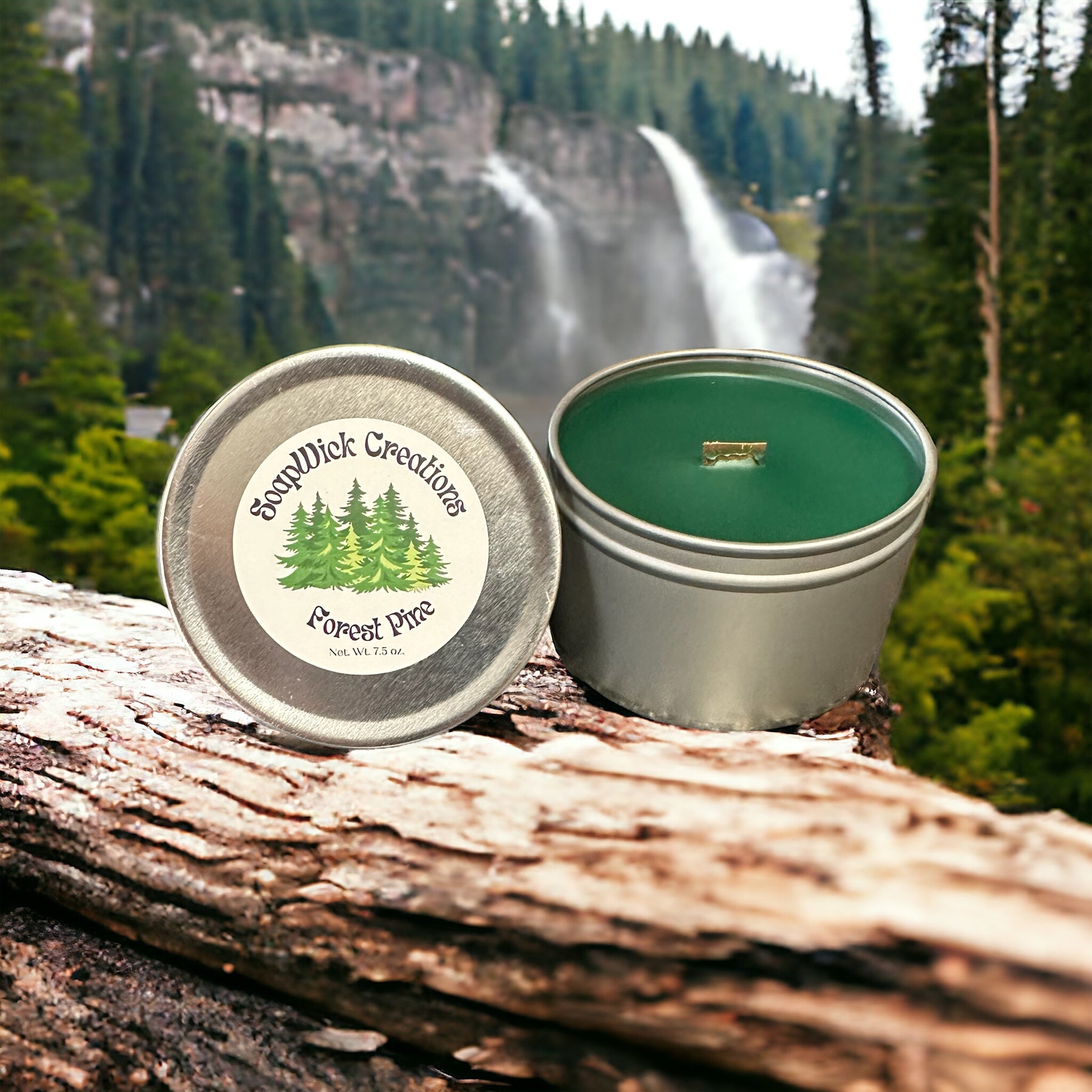 Forest Pine scented green colored candle in a silver metal tin with a pine forest and mountain with a waterfall in the background.