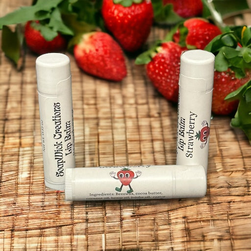 Three tubes of strawberry flavored lip balm sitting on a bamboo mat with strawberries in the background.