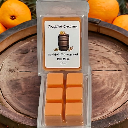 Applejack and orange peel scented wax melts sitting on a whiskey barrel with oranges in the background.