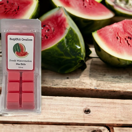 Fresh watermelon scented wax melts sitting on a wooden table with freshly cut watermelon in the background.