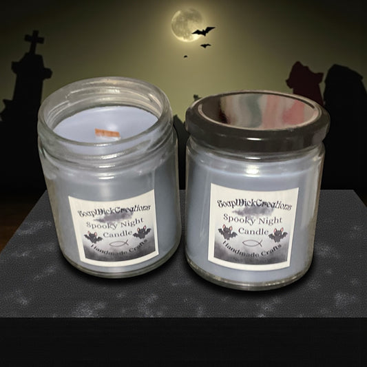 Two grayish colored candles on a dark night with the moon and bats in the background in a cemetery.