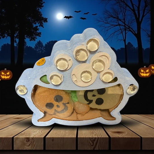 This is a wooden box painted and decorated by hand in the shape of a witches cauldron containing glycerin poured lavender and vampire blood scented soaps. It is sitting on a wooden table with a nighttime Woodland scene with pumpkins and bats in the background..