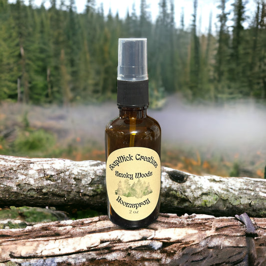 Photograph of a 2 ounce spray bottle containing “Smoky Woods” fragrance oil, Sitting on a log with a smoky  forest in the background.