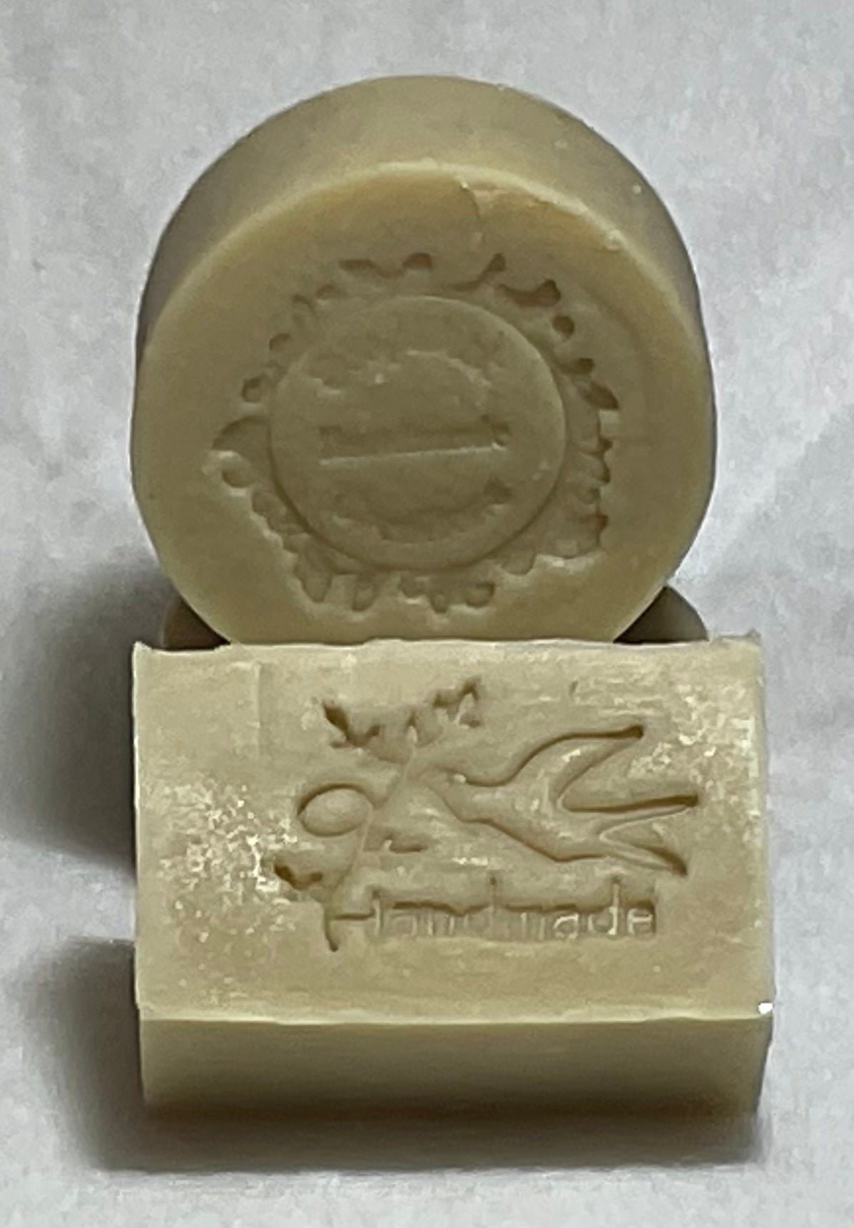 Photograph of a beige round men’s soap puck and bar soap