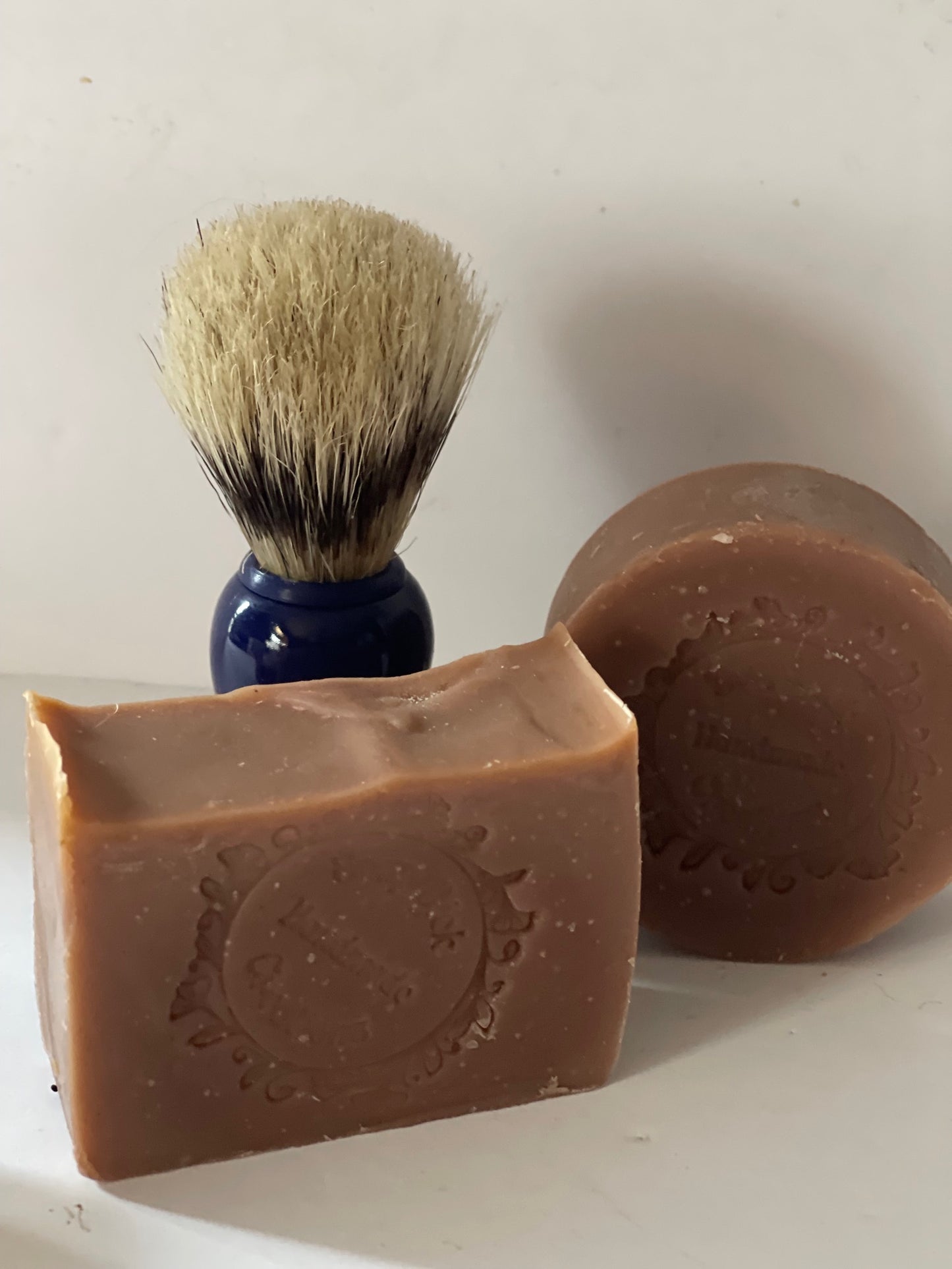 Photo of cherry tobacco mens soap bars and pucks, with a shaving brush in the background