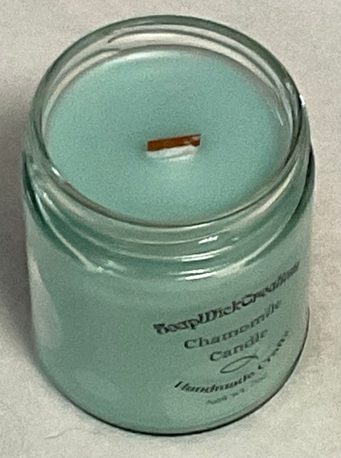 Photograph of light, mint colored candle with chamomile scent with the top removed.