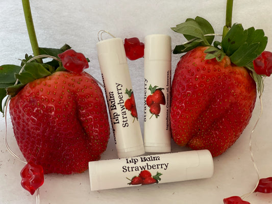 Picture of tubes of strawberry lip balm between two strawberries